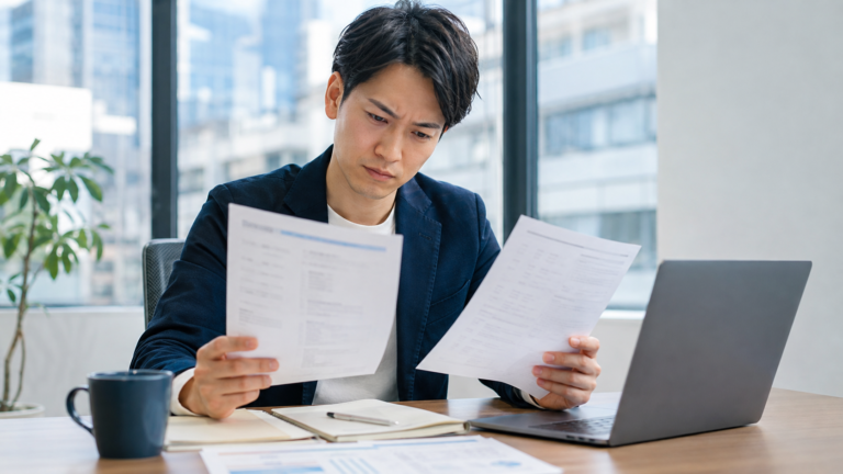 入社後に給与が違うと気づき給与明細と労働条件を確認する会社員