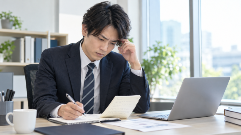仕事が覚えられず辞めたいと悩みメモを見ながら業務を確認する若手会社員